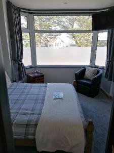 a bedroom with a bed and a chair and a window at Pensalda Guest House in Newquay