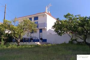 une maison blanche avec des arbres devant elle dans l'établissement Casa D'Avó (1º Andar), à Altura
