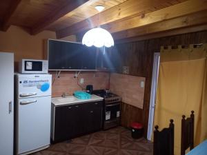 a kitchen with a white refrigerator and a stove at Departamento LA LILI in Uspallata +20 photos