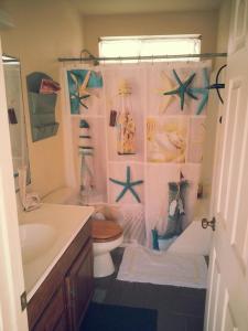 a bathroom with a shower curtain with a toilet and a sink at the Newport Family Peninsula Beach House in Newport Beach