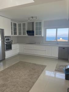 eine Küche mit weißen Schränken und einem großen Fenster in der Unterkunft Luxury Villa with amazing view, Cesme in Cesme