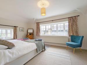 a bedroom with a bed and a blue chair at Flint Cottage , Emsworth in Emsworth