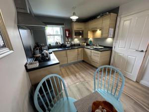 a kitchen with two chairs and a table and a counter at Seascape Apartment - Part of the The Bay Filey Holiday Village with pool, gym and direct beach access, pub, restaurant, tennis and meadows walks in Filey