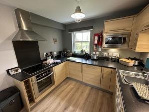 a kitchen with a stove top oven next to a sink at Seascape Apartment - Part of the The Bay Filey Holiday Village with pool, gym and direct beach access, pub, restaurant, tennis and meadows walks in Filey