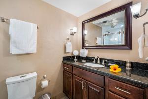 a bathroom with a sink and a toilet and a mirror at Kalanikai 306 in Kailua-Kona +15 photos