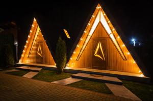a building with three large wooden doors with lights at Arhico Cabins in Satu Mare