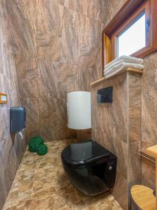 a bathroom with a black toilet and a window at Arhico Cabins in Satu Mare