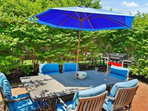 a table with a blue umbrella and chairs and a grill at Captain's Row: Pool, Tennis Chatham Charm in Chatham +37 photos