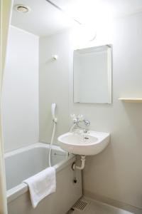 a white bathroom with a sink and a mirror at Shuzenji Onsen Hotel Takitei in Izu