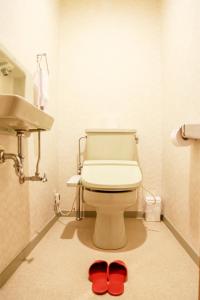 ein Bad mit WC und roten Hausschuhen auf dem Boden in der Unterkunft Shuzenji Onsen Hotel Takitei in Izu