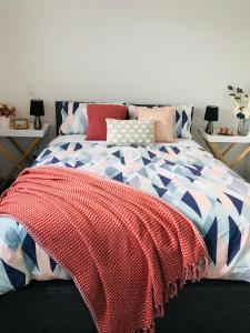 a bedroom with a bed with a red and blue comforter at Perfect modern Townhouse CBD Christchurch in Christchurch