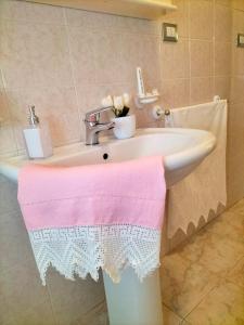 een wastafel in de badkamer met een roze en witte handdoek erop bij B&B Rosa dei Venti in Sorso