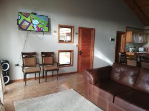 a living room with a brown leather couch and chairs at Preciosa Casa en Parcela con chimenea 3d 2b in Villarrica