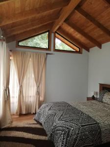 a bedroom with a bed and two windows at Preciosa Casa en Parcela con chimenea 3d 2b in Villarrica