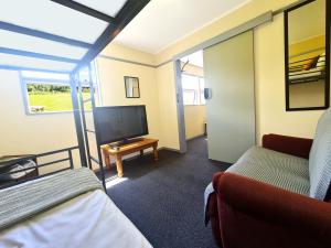 a living room with a tv and a couch at Rarakau Lodge in Tuatapere