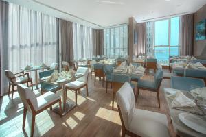 a restaurant with tables and chairs and windows at TRYP by Wyndham Abu Dhabi City Center in Abu Dhabi