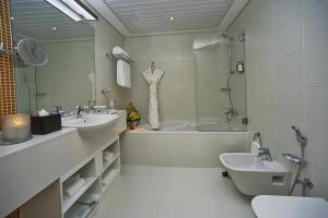 a bathroom with two sinks and a tub and a toilet at TRYP by Wyndham Abu Dhabi City Center in Abu Dhabi