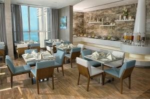 a restaurant with blue tables and chairs and a large window at TRYP by Wyndham Abu Dhabi City Center in Abu Dhabi