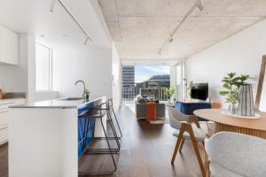 a kitchen and living room with a table and chairs at The Chromatic Apartments by Urban Rest in Sydney