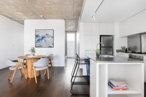 a kitchen and dining room with white walls and a table at The Chromatic Apartments by Urban Rest in Sydney