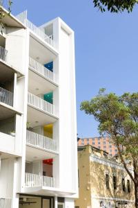an apartment building with white balconies and a tree at The Chromatic Apartments by Urban Rest in Sydney