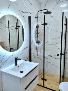 bagno con lavandino bianco e specchio di Apartment Talarowa Delux a Varsavia