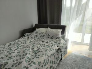 un letto con piumone verde e bianco e una finestra di Apartment Talarowa Delux a Varsavia