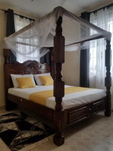 a bedroom with a canopy bed with yellow pillows at Cozy Apartment - Nyali Mombasa in Mombasa