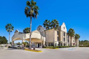 Gray的住宿－Best Western Houma Inn，停车场内一座棕榈树成荫的大型白色建筑