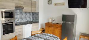 Una cocina con refrigerador de acero inoxidable y una mesa. en Moliets plage, Résidence OPEN SUD, en Moliets-et-Maa