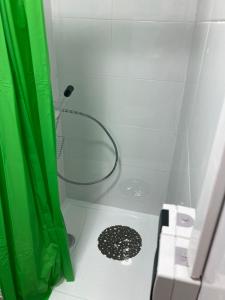 a shower with a green shower curtain and a drain at little paradise in Montcada i Reixac