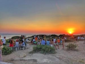 un grupo de personas sentadas en la playa viendo la puesta de sol en Holiday Home Sicily Talia che Bed-du en Punta Braccetto