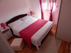 ein Schlafzimmer mit einem großen Bett mit einer roten und weißen Decke in der Unterkunft Apartments Linda in Trogir