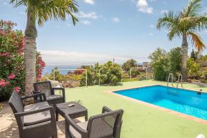 un patio con sedie, una piscina e l'oceano di Lightbooking Luymar con piscina Villa de Mazo a Mazo