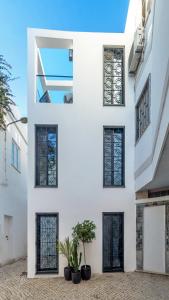 un edificio bianco con finestre nere e piante in vaso di Casa Mimi by Larimar a Olhão