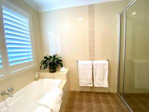 a bathroom with a tub and a plant and towels at Casuarina Beach 2 bedroom retreat in Casuarina