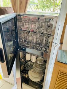 einen offenen Kühlschrank mit Geschirr und Tellern in der Unterkunft 1BD 1BA PENTHOUSE 2X QUEEN in Nasugbu