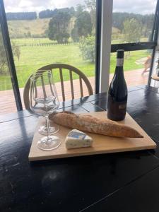 a bottle of wine and a glass and cheese on a table at Shibui Lilydale Luxury Romance in Lilydale
