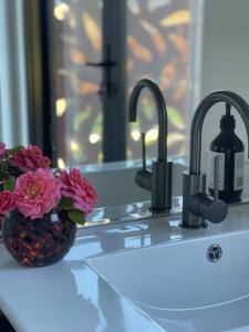 a bathroom sink with two faucets and a vase of flowers at Shibui Lilydale Luxury Romance in Lilydale