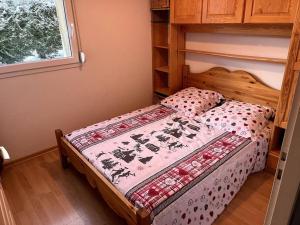 a small bedroom with a bed with aspread on it at Le petit bonhomme de neige in Gérardmer