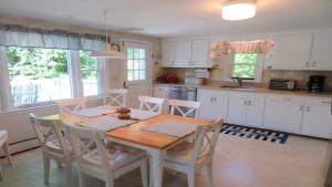 a kitchen with a table and chairs and a kitchen with white cabinets at 14 Capri Lane Chatham Cape Cod - The Cape House in Chatham