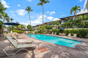 a swimming pool with lounge chairs and an umbrella at Casa De Emdeko 222 in Kailua-Kona