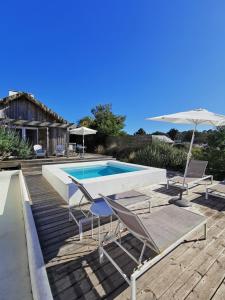 a swimming pool with two chairs and an umbrella at Casas na Lagoa - Carvalhal in Carvalhal