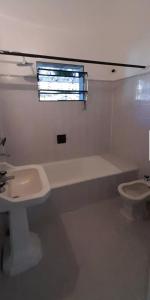 Baño blanco con lavabo y aseo en La casa de las Luces en Villa Carlos Paz