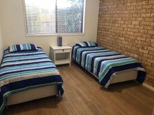 a bedroom with two beds and a brick wall at Unit 2, 36 Sunderland Street Evans Head in Evans Head