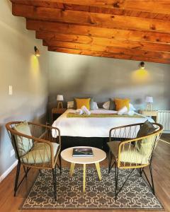 een slaapkamer met een bed met 2 stoelen en een tafel bij Desierto Suites in El Chalten
