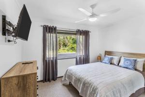 een slaapkamer met een bed, een tv en een raam bij Pearl On Beech 125 Beech Street in Evans Head