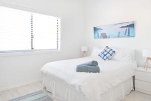 a white bedroom with a bed with a stuffed animal on it at Sunrise on Terrace Unit 3, 21 Terrace Street Evans Head in Evans Head