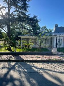 una cerca con un árbol delante de un edificio en La casa de las Luces en Villa Carlos Paz
