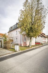una casa blanca con un árbol al lado de una calle en Haus Alpenruhe en Bad Reichenhall